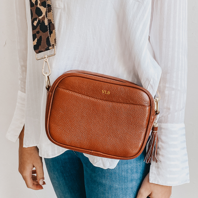 Brown leather bag being worn with white top and blue jeans