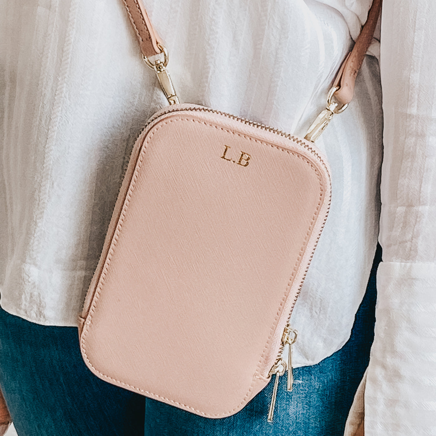 Personalised icy pink leather bag being held against a white shirt and blue jeans