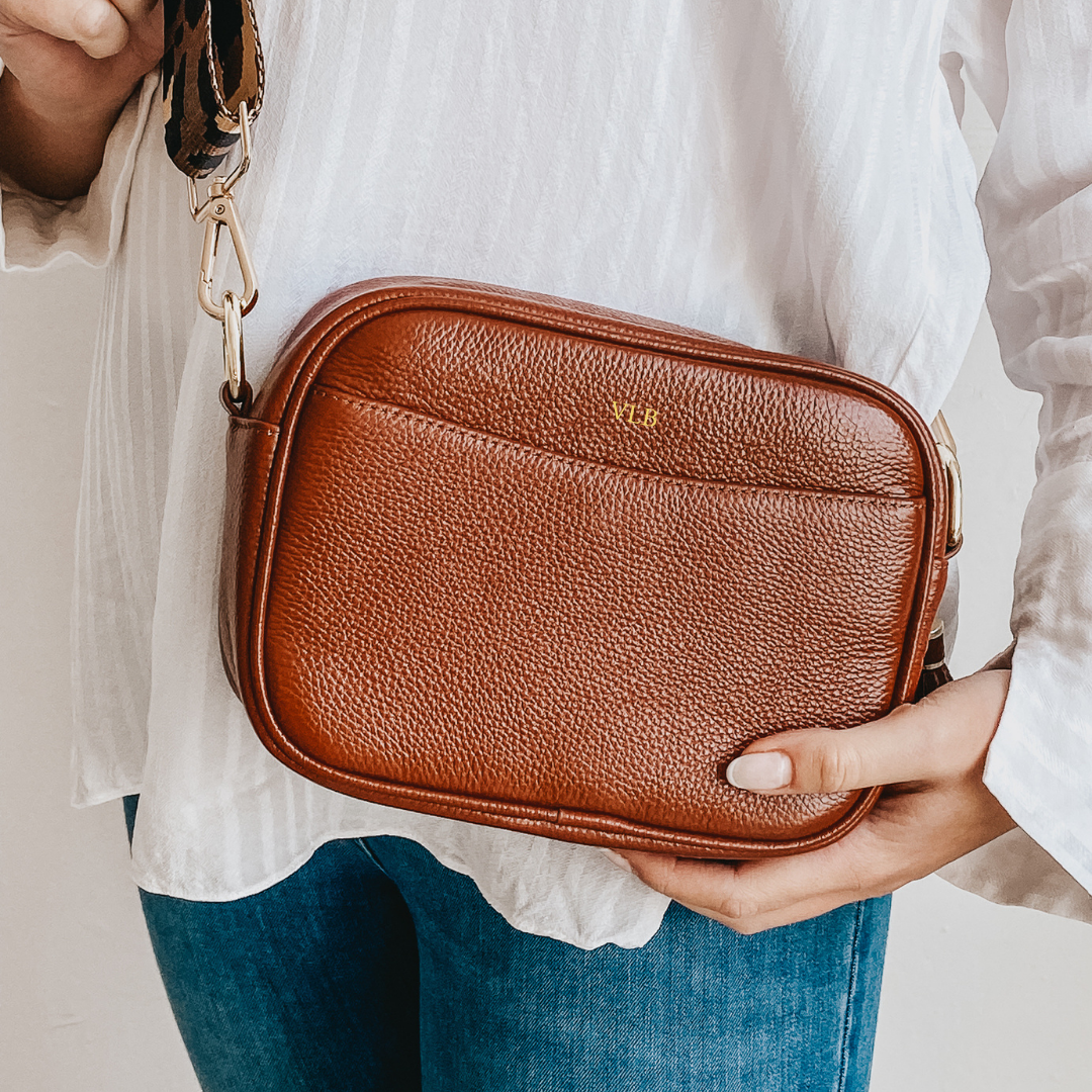Brown leather bag being worn with white top and blue jeans