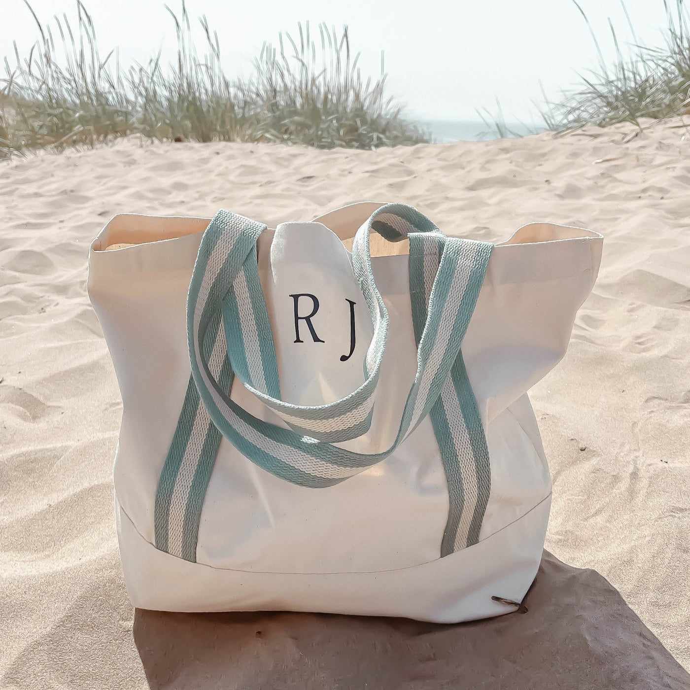 Cotton beach bag in natural with aqua handles and personalised with navy initials
