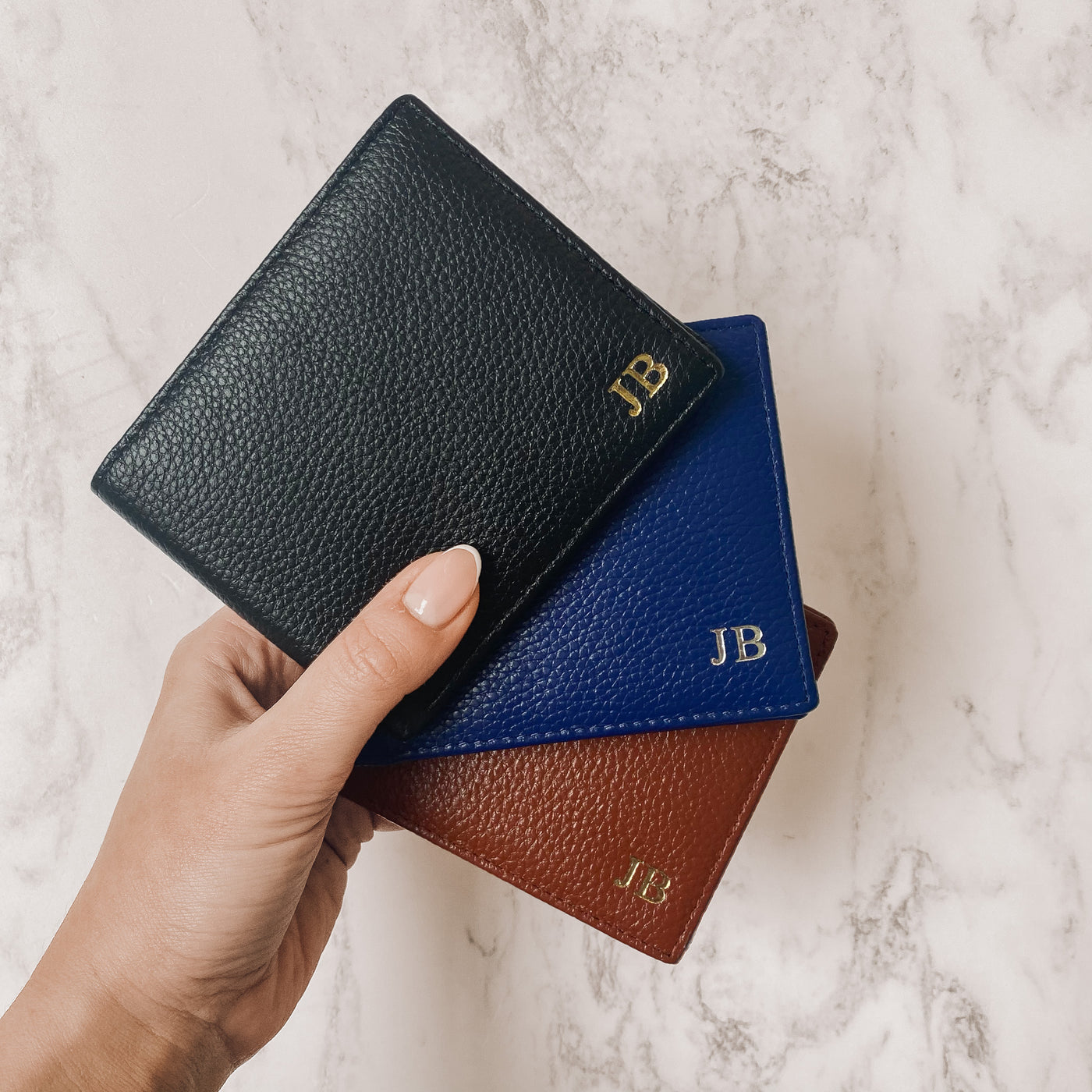 black, blue and tan mens wallet held on a marble background