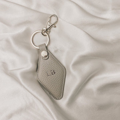 stone diamond keyring with gold hardware  on a silk backdrop. the keyring is embossed with the initials LB